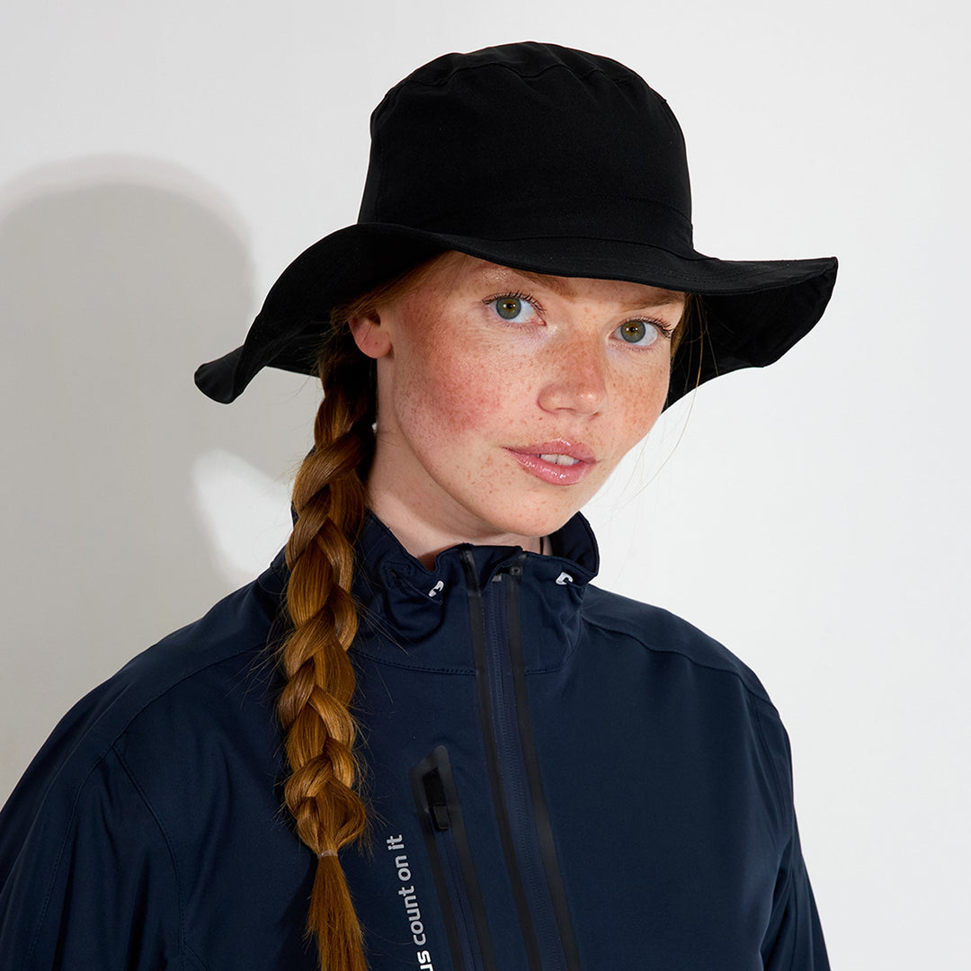 Person wearing a black hat and navy jacket with a white background