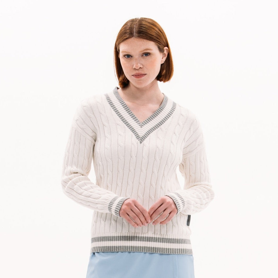 Woman wearing a white sweater with a V-neck and a light blue skirt on a white background