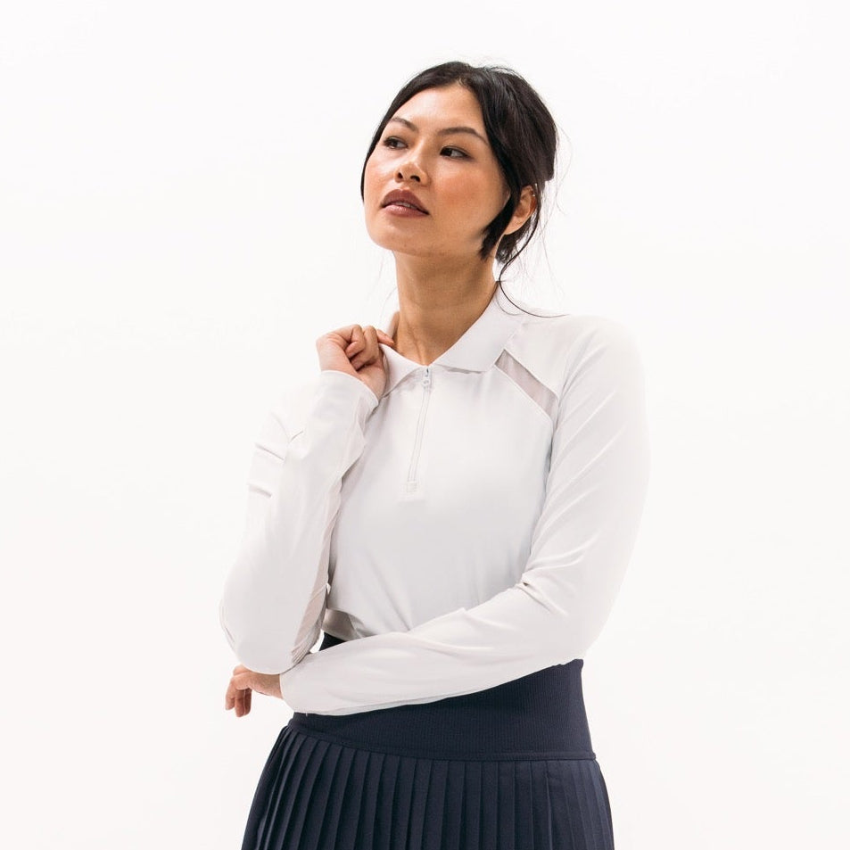 Woman wearing a white blouse and navy pleated skirt on a white background