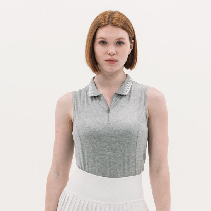 Woman wearing a sleeveless gray top and white pleated skirt on a white background