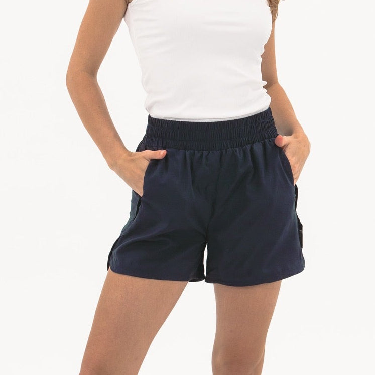 Woman wearing navy shorts and a white top on a white background