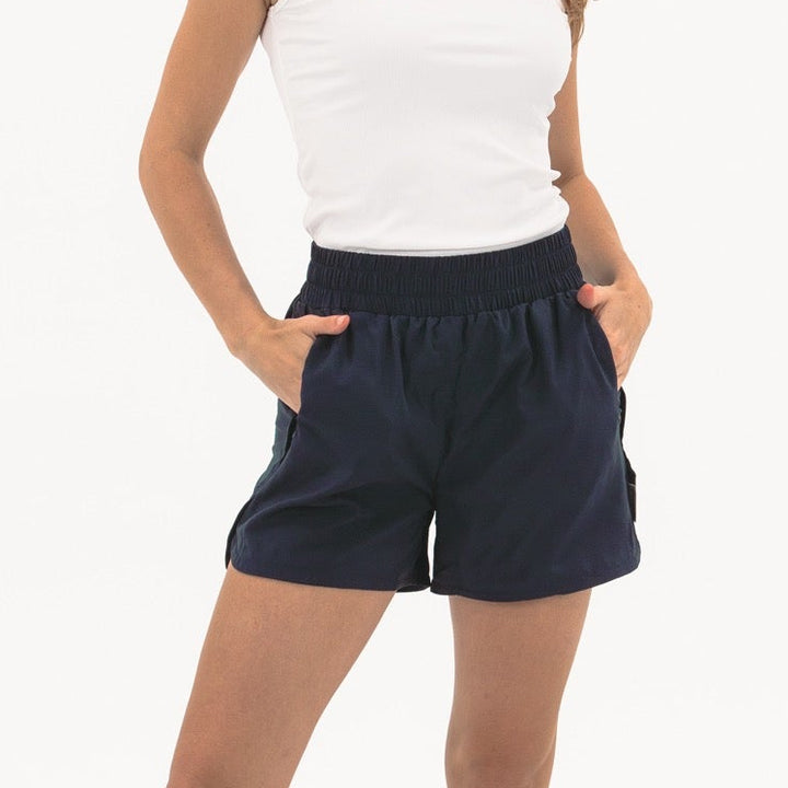 Woman wearing navy shorts and a white top on a white background