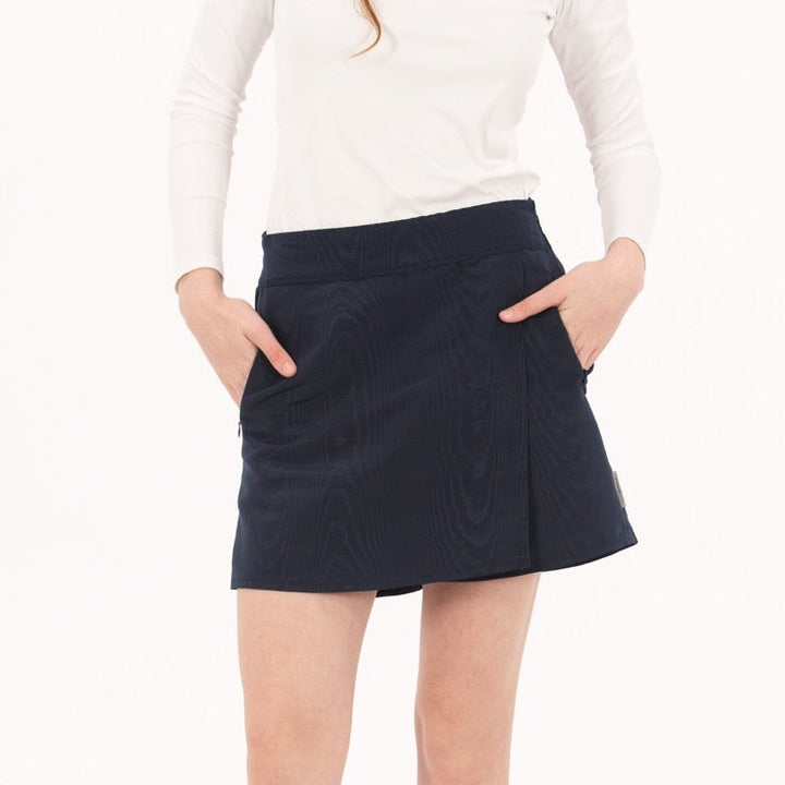 Woman wearing a white long-sleeve top and navy skirt on a white background