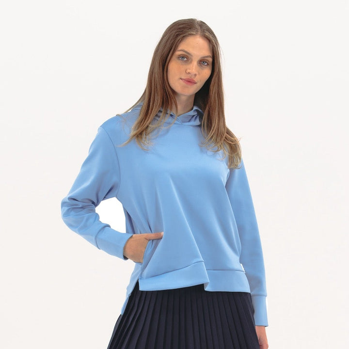 Woman wearing a light blue hoodie and black pleated skirt on a white background