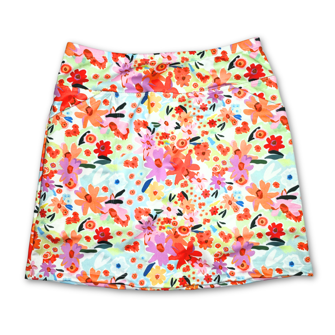 A women's A-line mini skirt with a vibrant, multicolor watercolor floral print on a white base, featuring orange, pink, red, and purple flowers with green and blue accents.
